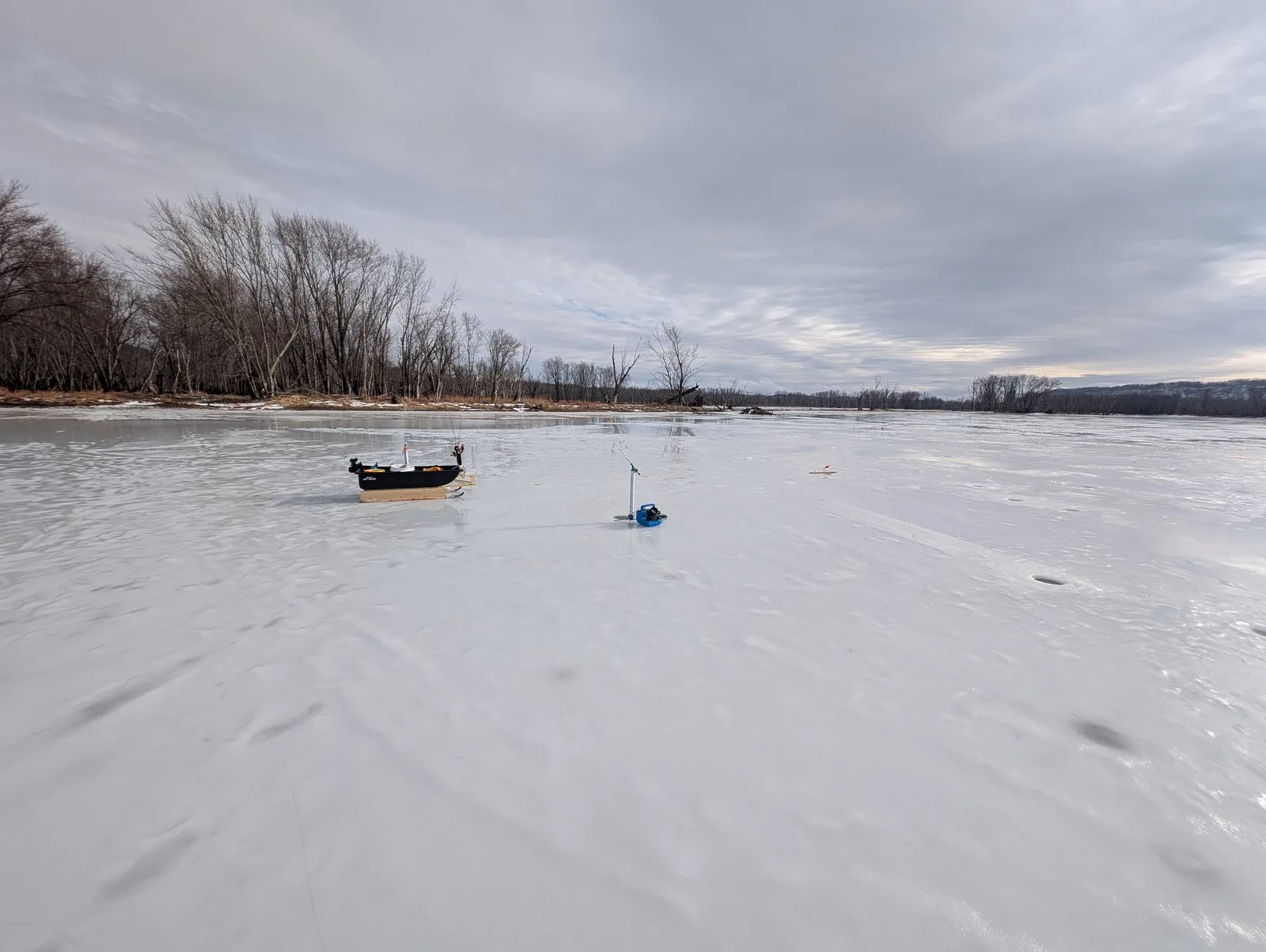 Ice fishing sled and auger on a frozen lake